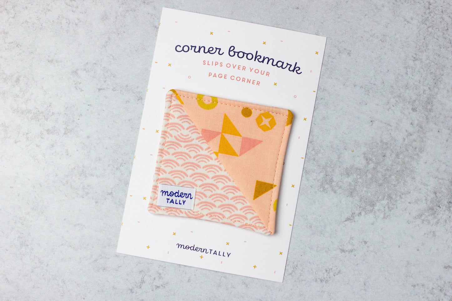Corner bookmark handmade out of fabric, peach with geometric designs.