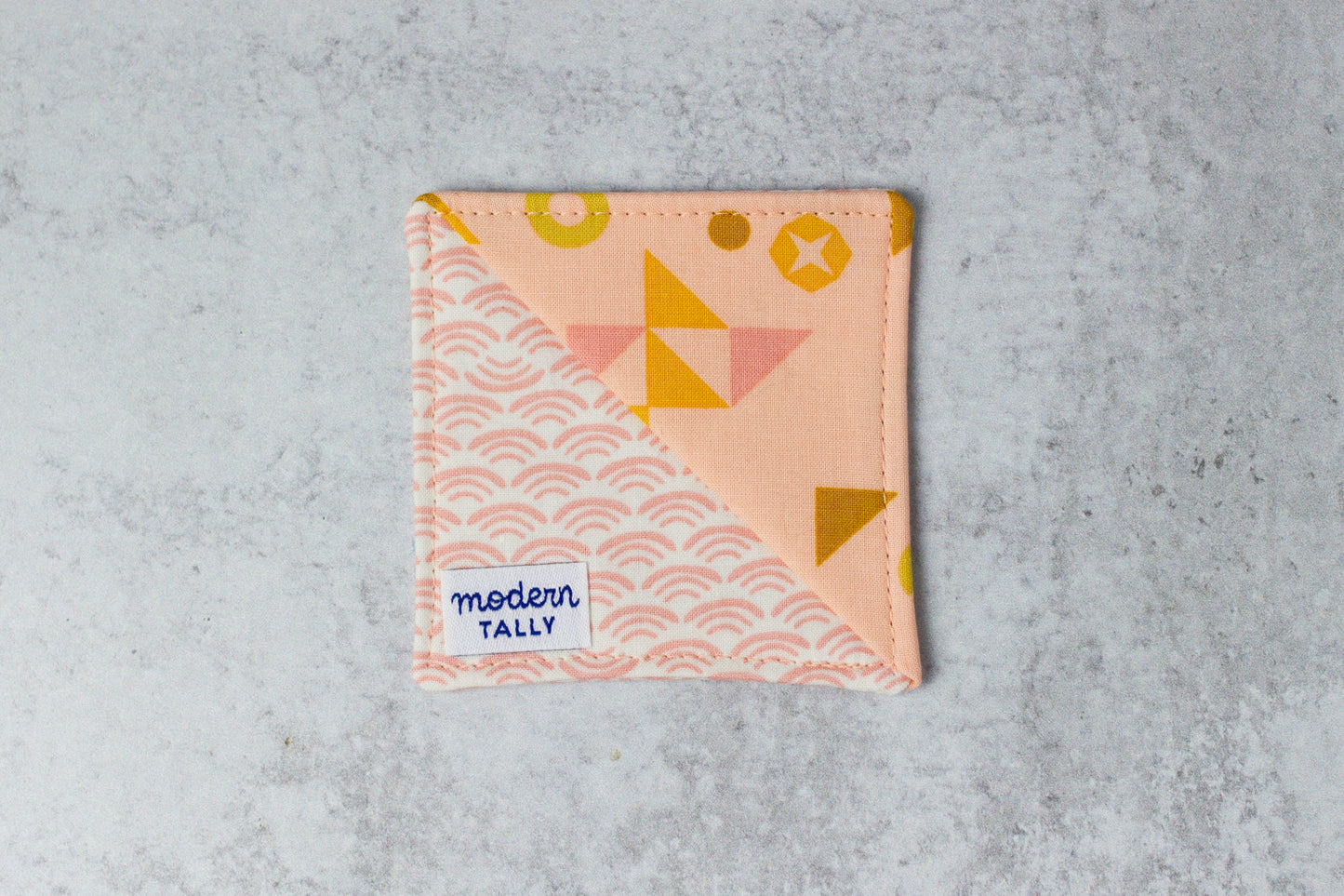 Corner bookmark handmade out of fabric, peach with geometric designs.