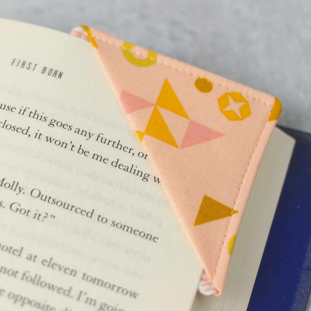 Corner bookmark handmade out of fabric, peach with geometric designs.